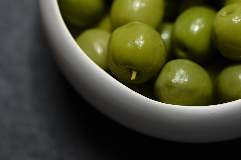 una ciotola bianca piena di olive verdi su un tavolo
