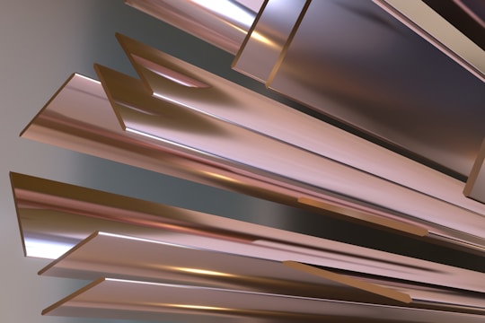 A collection of metallic, angular, and reflective surfaces arranged in a dynamic and abstract composition. The surfaces reflect subtle gradients of light and shadows, creating a sense of depth and movement.