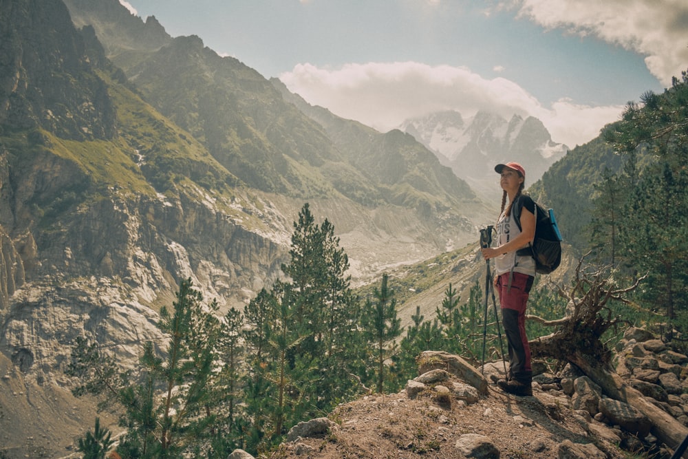 a woman with a backpack standing on top of a mountain