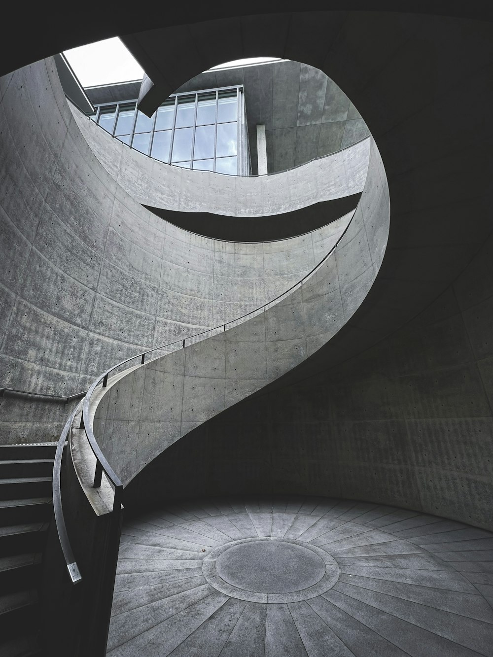 a spiral staircase in a building with a circular window
