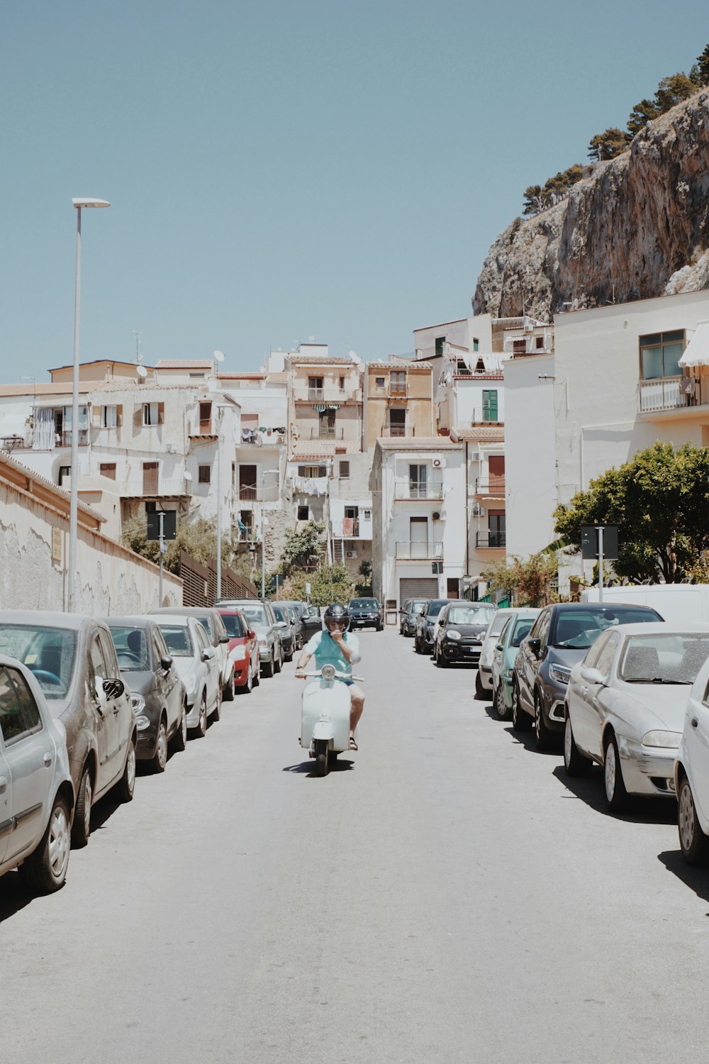 a woman riding a skateboard down a street next to parked cars