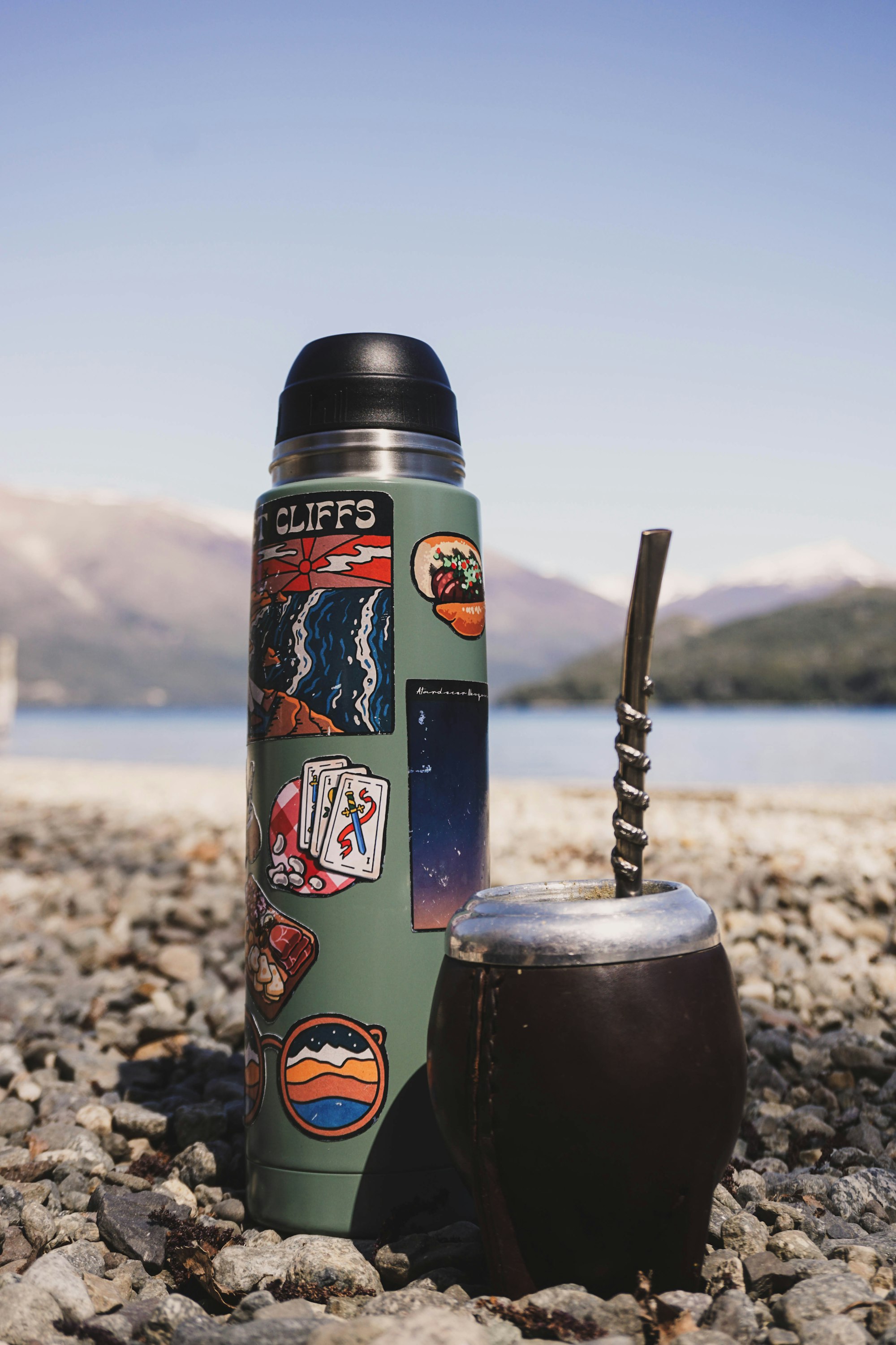 mate y termo con stickers en un paisaje lacustre de la patagonia argentina
