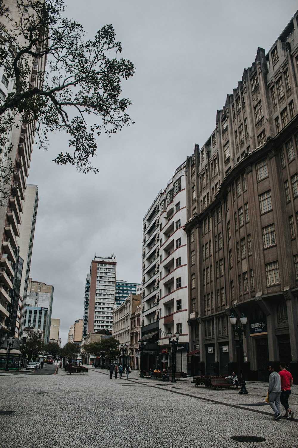 a group of people walking down a street next to tall buildings