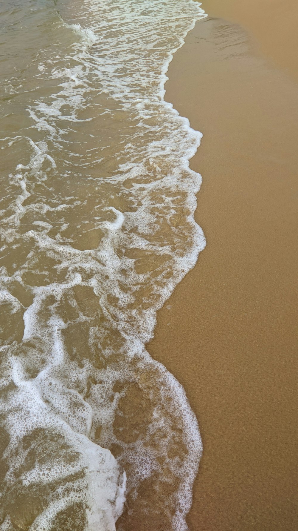 a sandy beach with waves coming in to shore