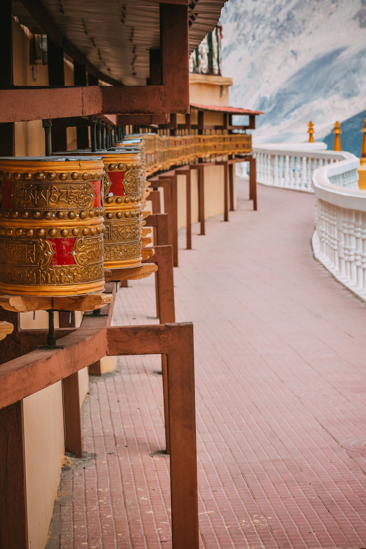 Monk in maroon robes inside a Himalayan monastery with prayer wheels and ancient murals