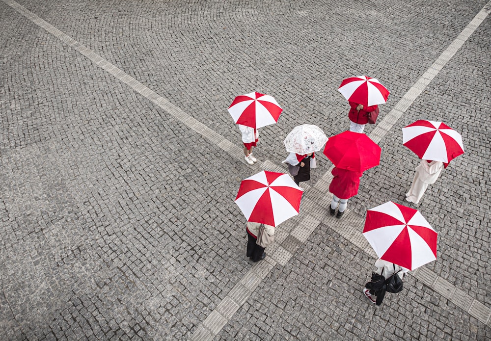 a group of people with red and white umbrellas