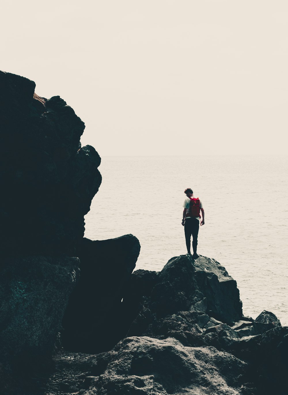 Un uomo in piedi sulla cima di una roccia vicino all'oceano