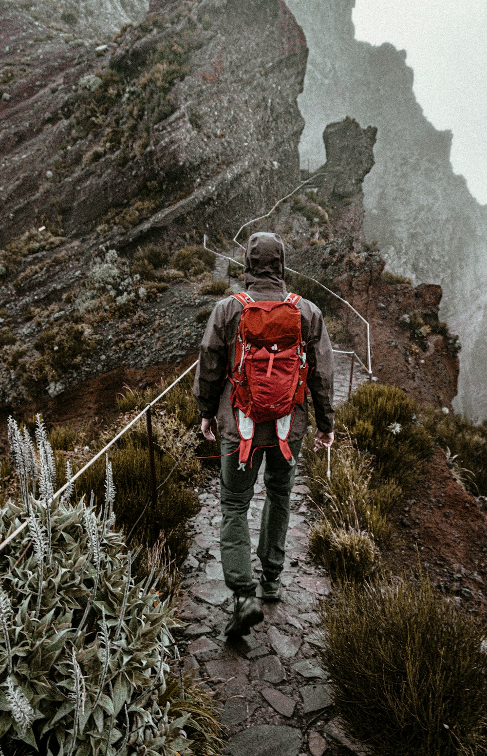 a man with a red backpack walking up a mountain