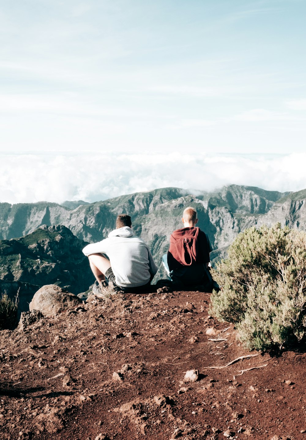 a couple of people sitting on top of a mountain