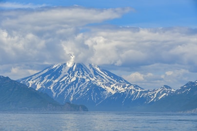 a mountain covered in snow on top of a body of water