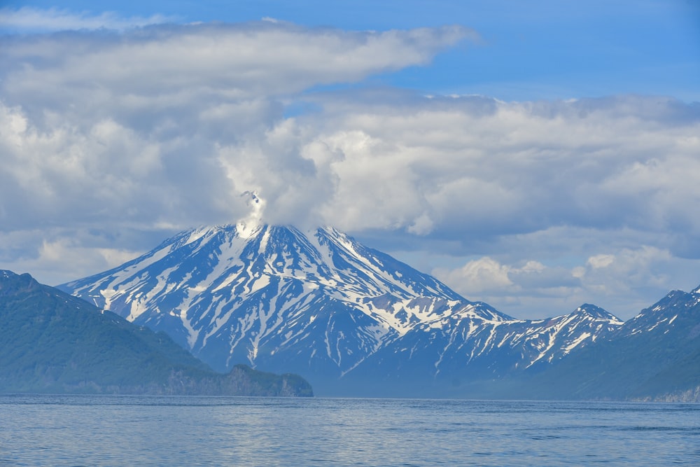 a mountain covered in snow on top of a body of water