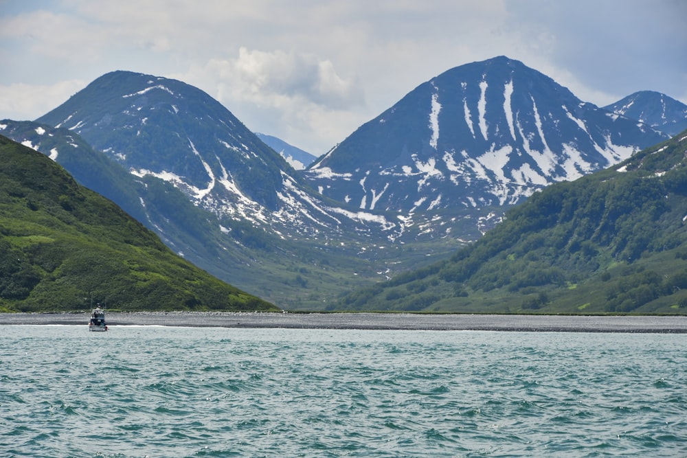 a boat in a body of water with mountains in the background