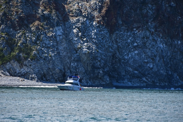 A clear blue sea with a boat anchored near a rocky shore during water refill service.