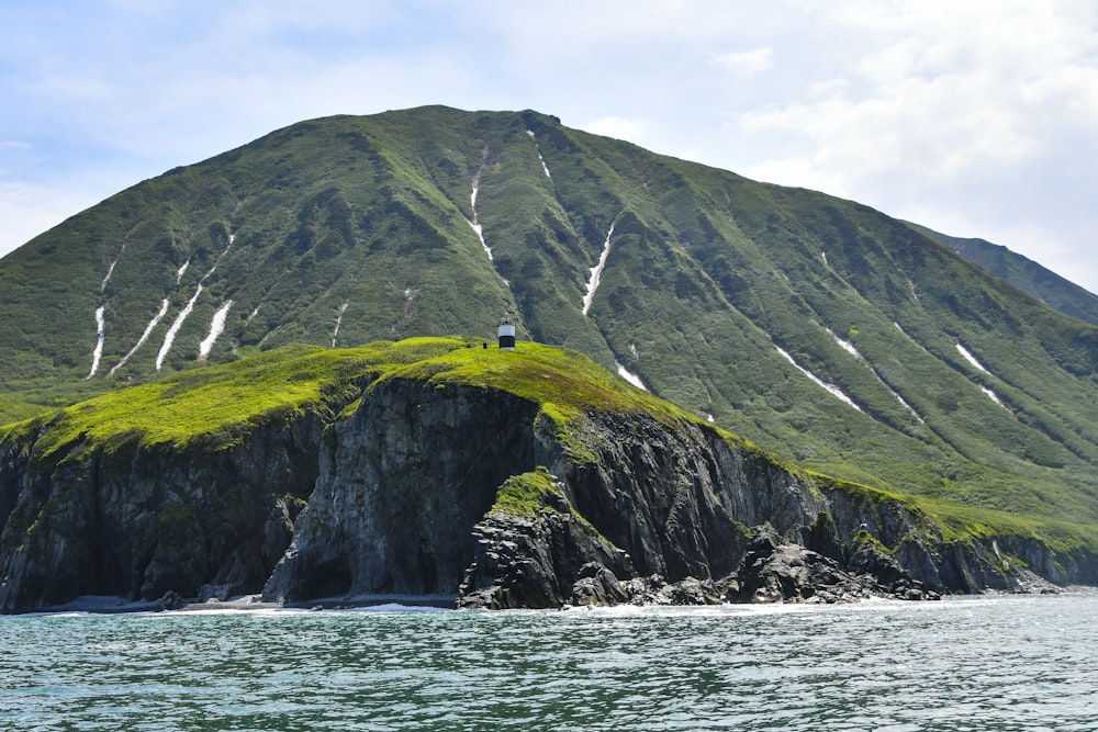 a large green mountain with a person standing on top of it