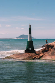 a man standing on top of a rock next to a light house