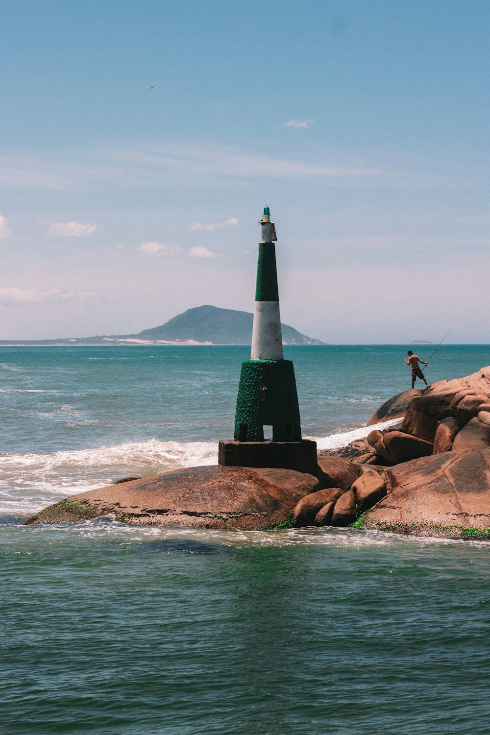 a man standing on top of a rock next to a light house