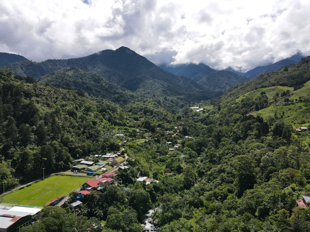 a lush green valley surrounded by mountains under a cloudy sky