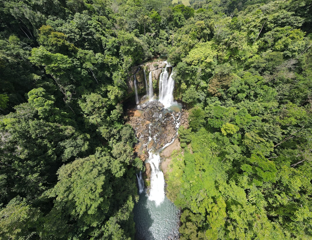 a waterfall in the middle of a forest, An aerial drone photo of Nauyaca Waterfalls.
