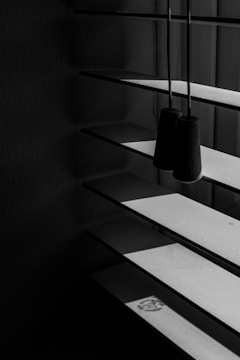 Vertical blinds with an interplay of light and shadow creating a striped pattern on the surfaces. The scene is minimalist, with the focus on the structure of the blinds and the contrasting dark and light areas.