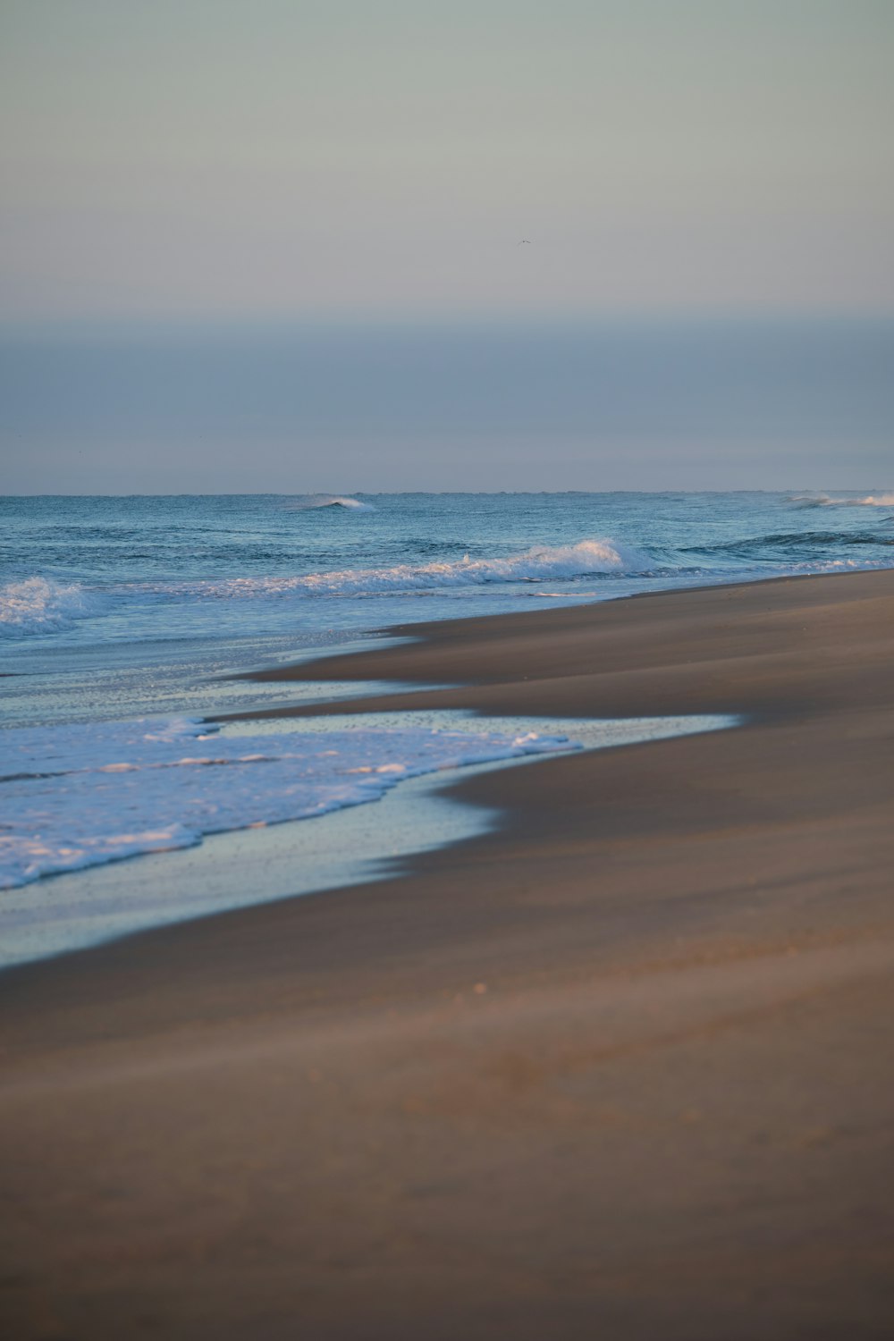 a person walking on a beach with a surfboard