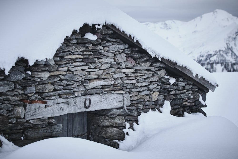 un piccolo edificio in pietra con un tetto coperto di neve