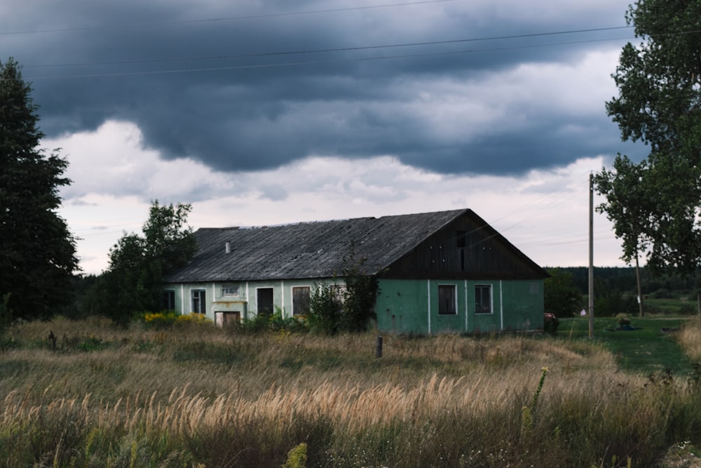 a house in the middle of a field with a stormy sky in the background