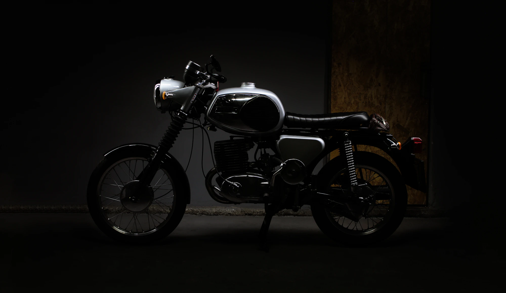 Moto clásica aparcada en un garaje oscuro iluminado con luz cálida