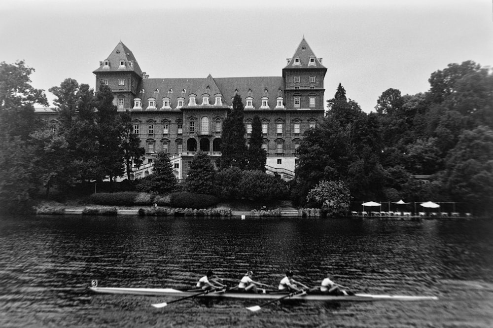 a black and white photo of two rowers in front of a castle