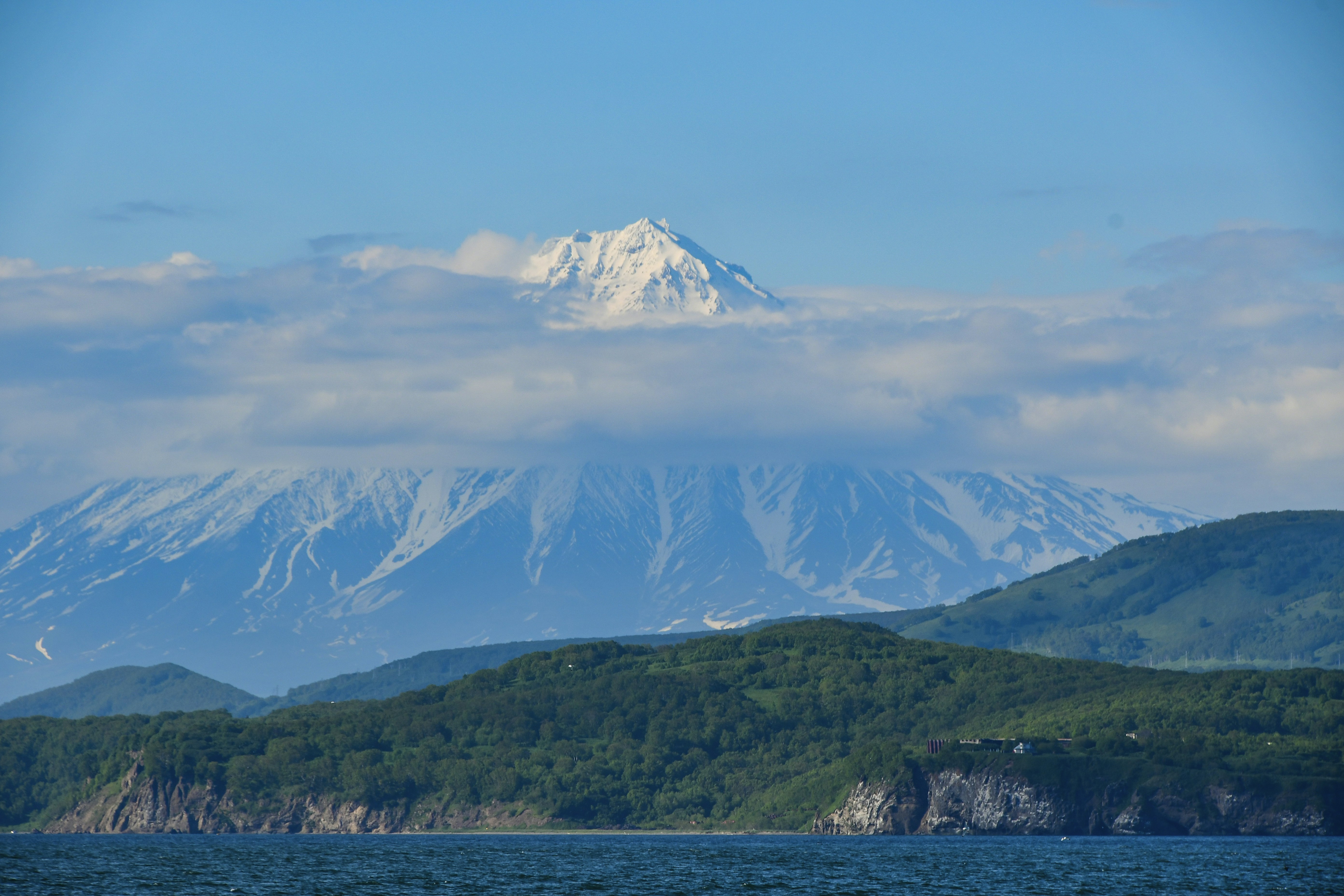 a snow covered mountain in the distance with a body of water in front of it