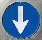 a close up of a blue sign with a white arrow