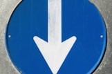 a close up of a blue sign with a white arrow