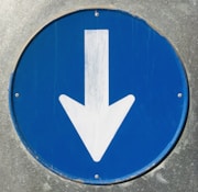 a close up of a blue sign with a white arrow