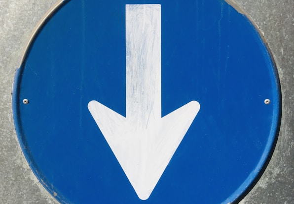 a close up of a blue sign with a white arrow
