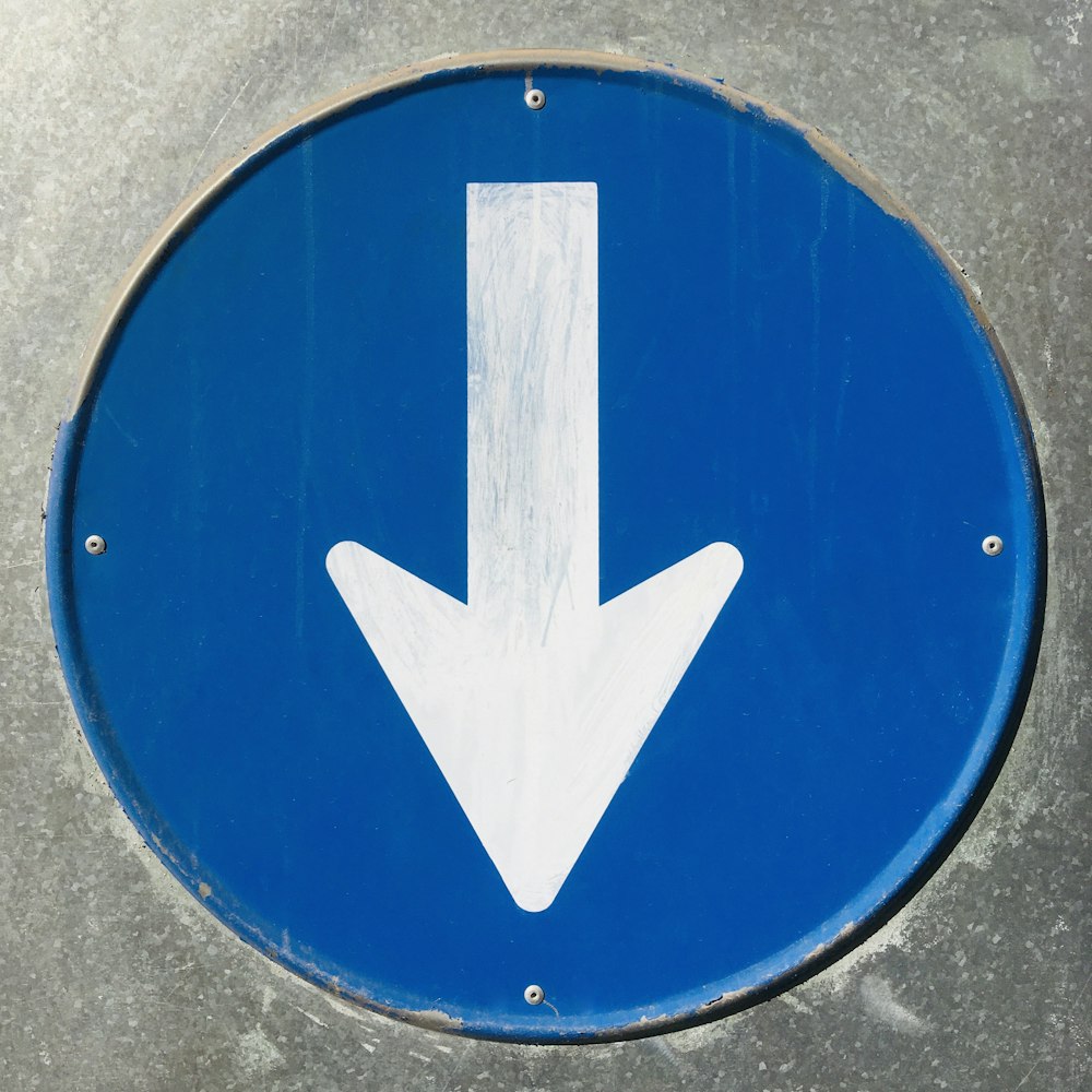 a close up of a blue sign with a white arrow