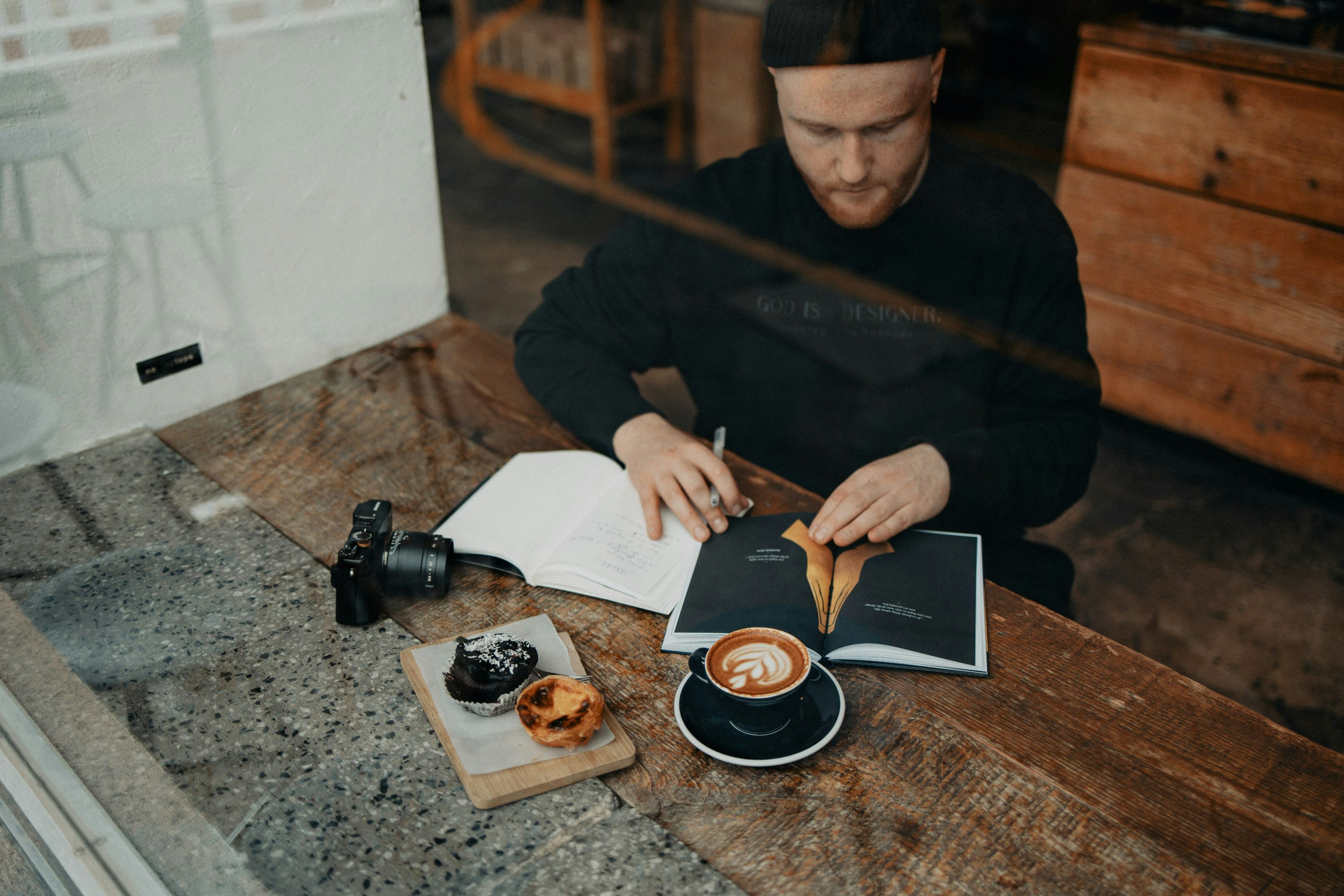 a man sitting at a table with a book and a cup of coffee