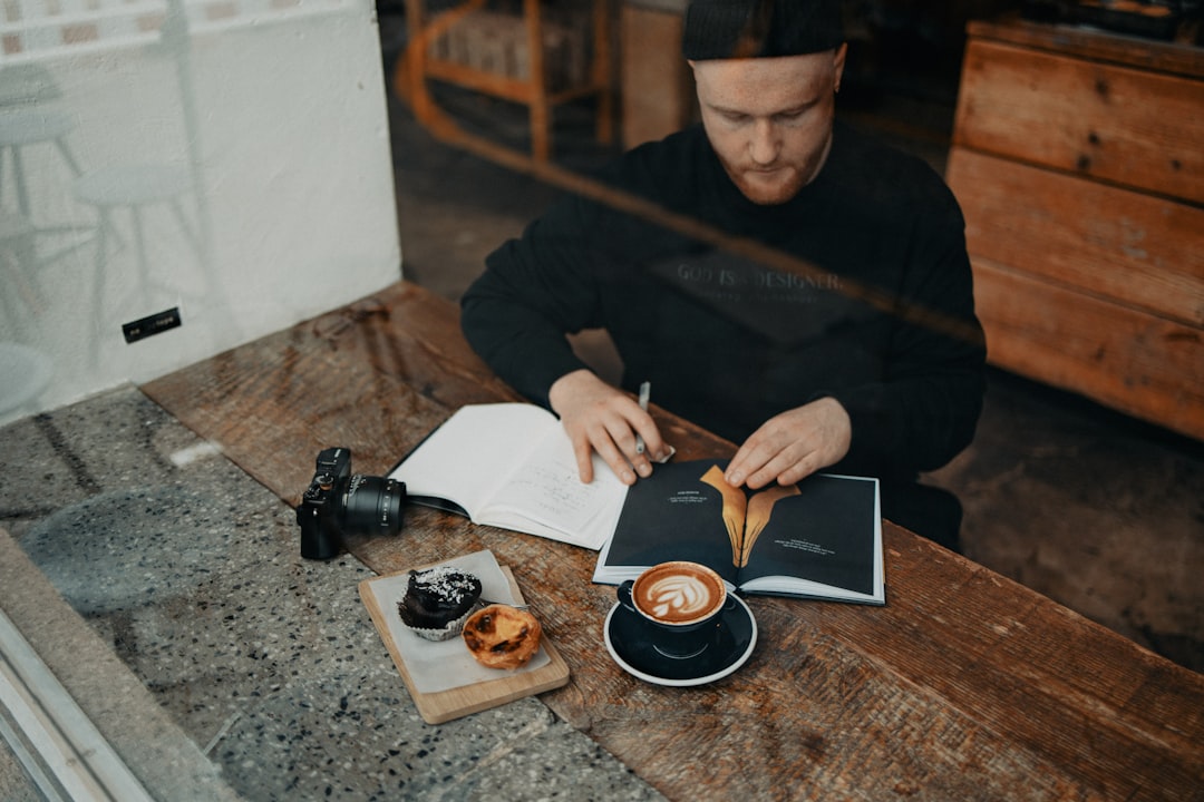 a man sitting at a table with a book and a cup of coffee, Finde Zukunft Journaling