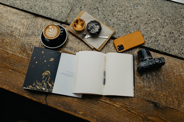 an open book sitting on top of a wooden table next to a cup of coffee