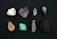 A collection of eight distinct mineral stones arranged in two rows against a dark background. The stones exhibit a variety of colors and textures, ranging from white to deep green and black, with some displaying a crystalline structure.
