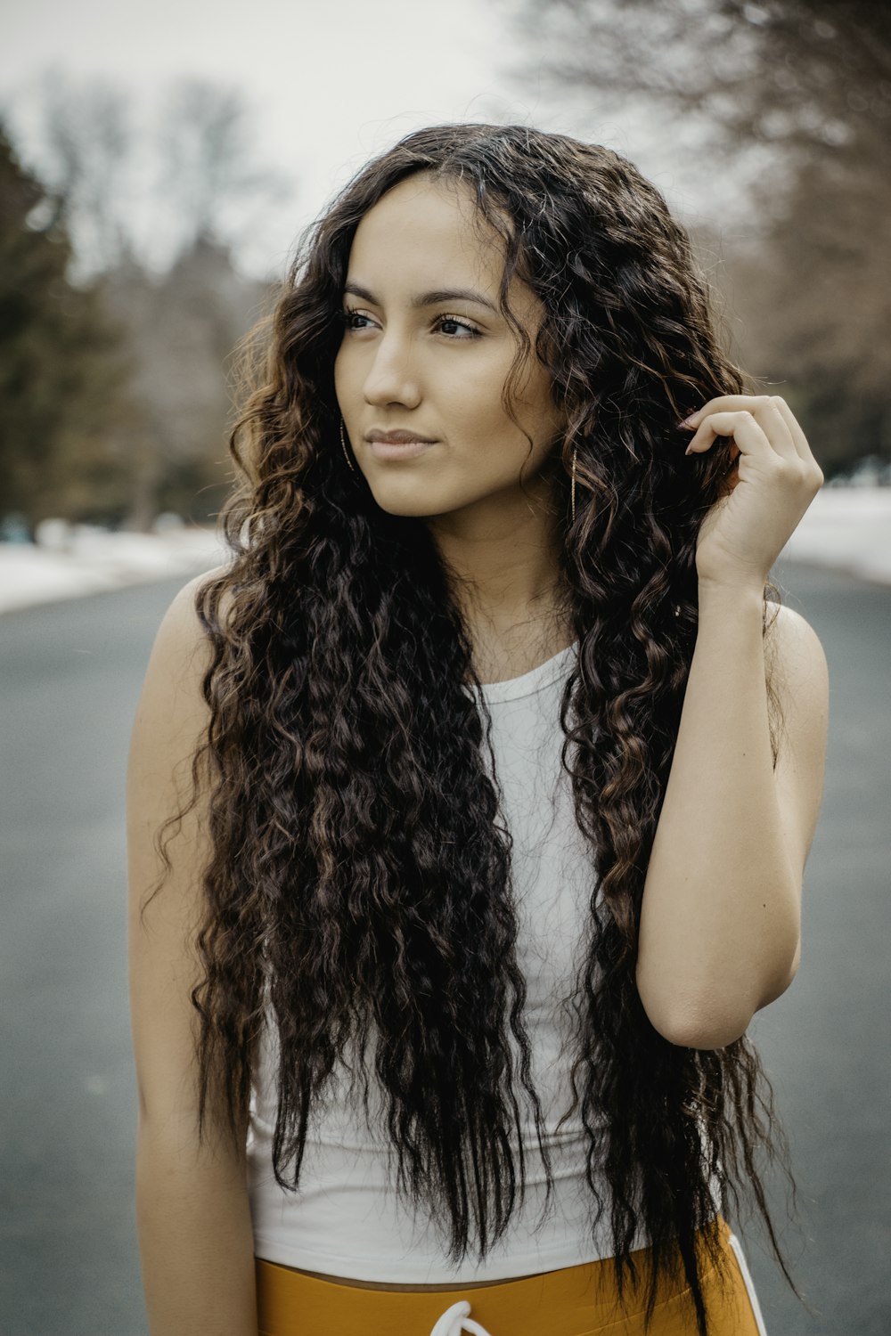 a woman with long curly hair standing in the street