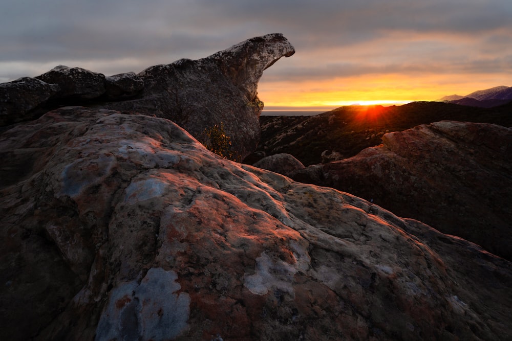 a rock formation with the sun setting in the background
