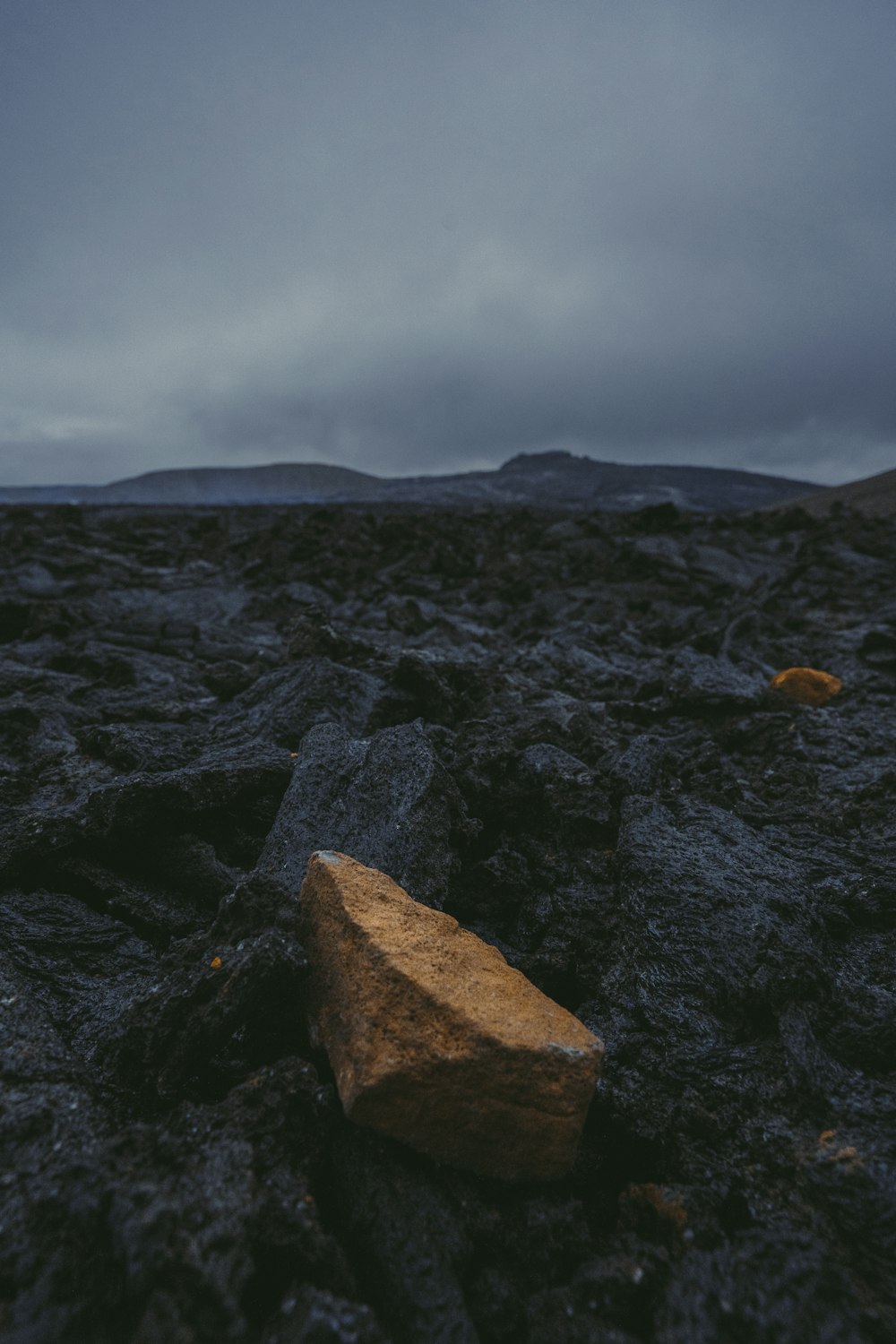 a rock on the ground with a cloudy sky in the background