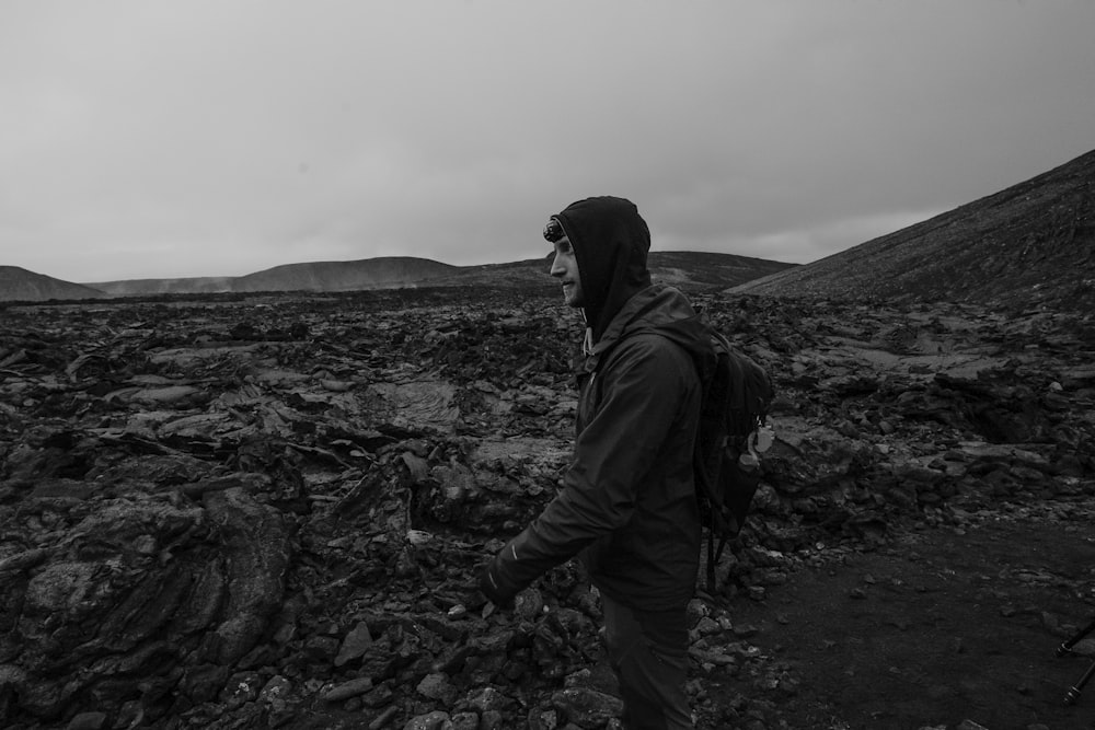 a man with a backpack walking through a rocky field