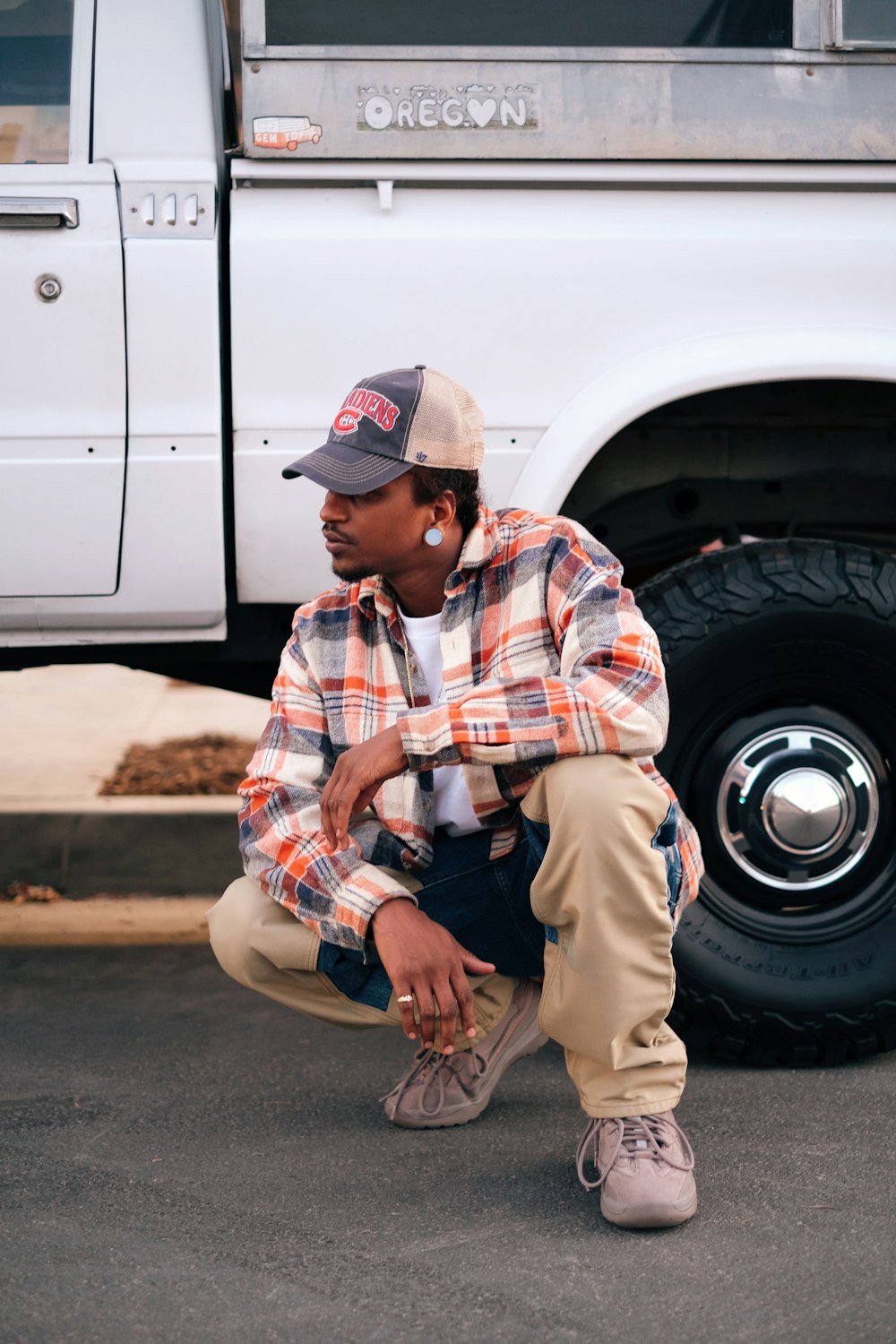 a man squatting in front of a white truck