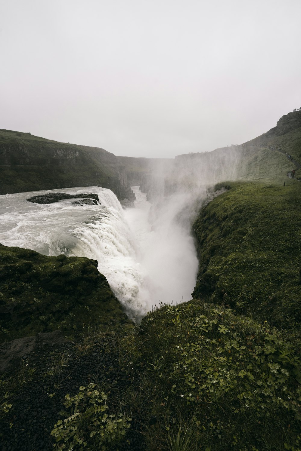 a large waterfall in the middle of a lush green field