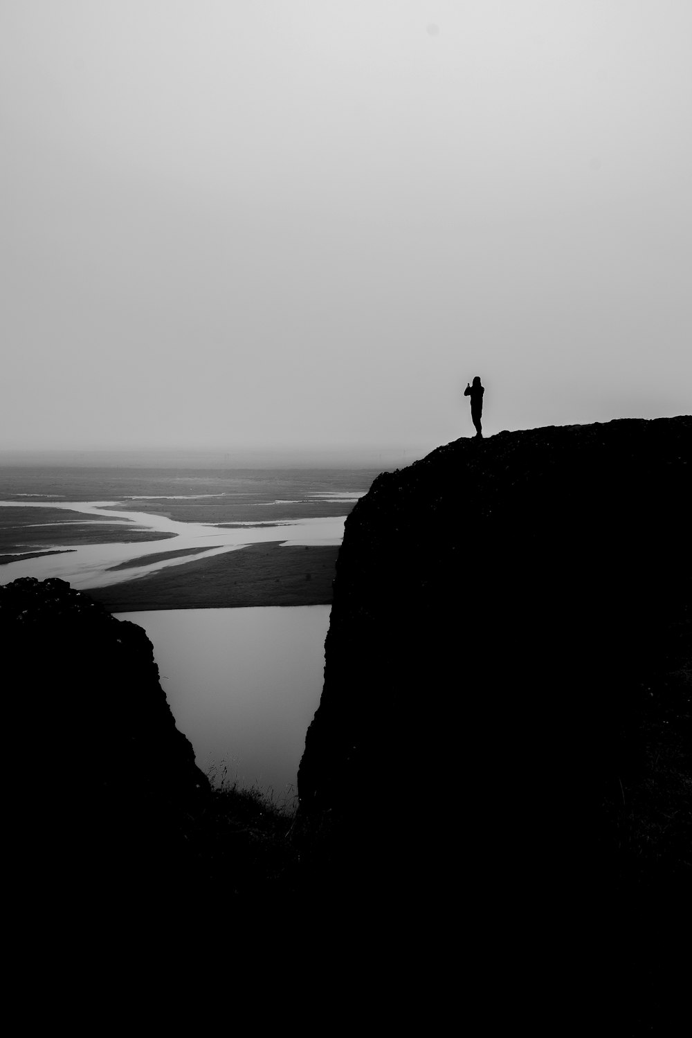 une personne debout au sommet d’une colline à côté d’un plan d’eau