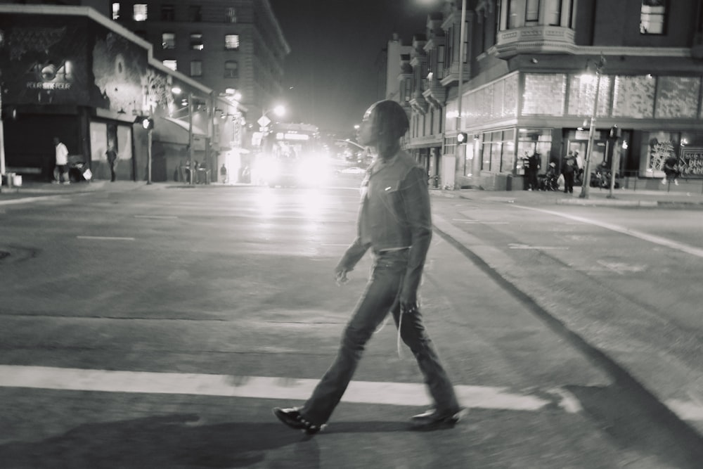 a woman walking across a street at night