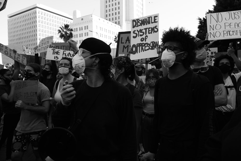 a group of people holding signs and wearing masks