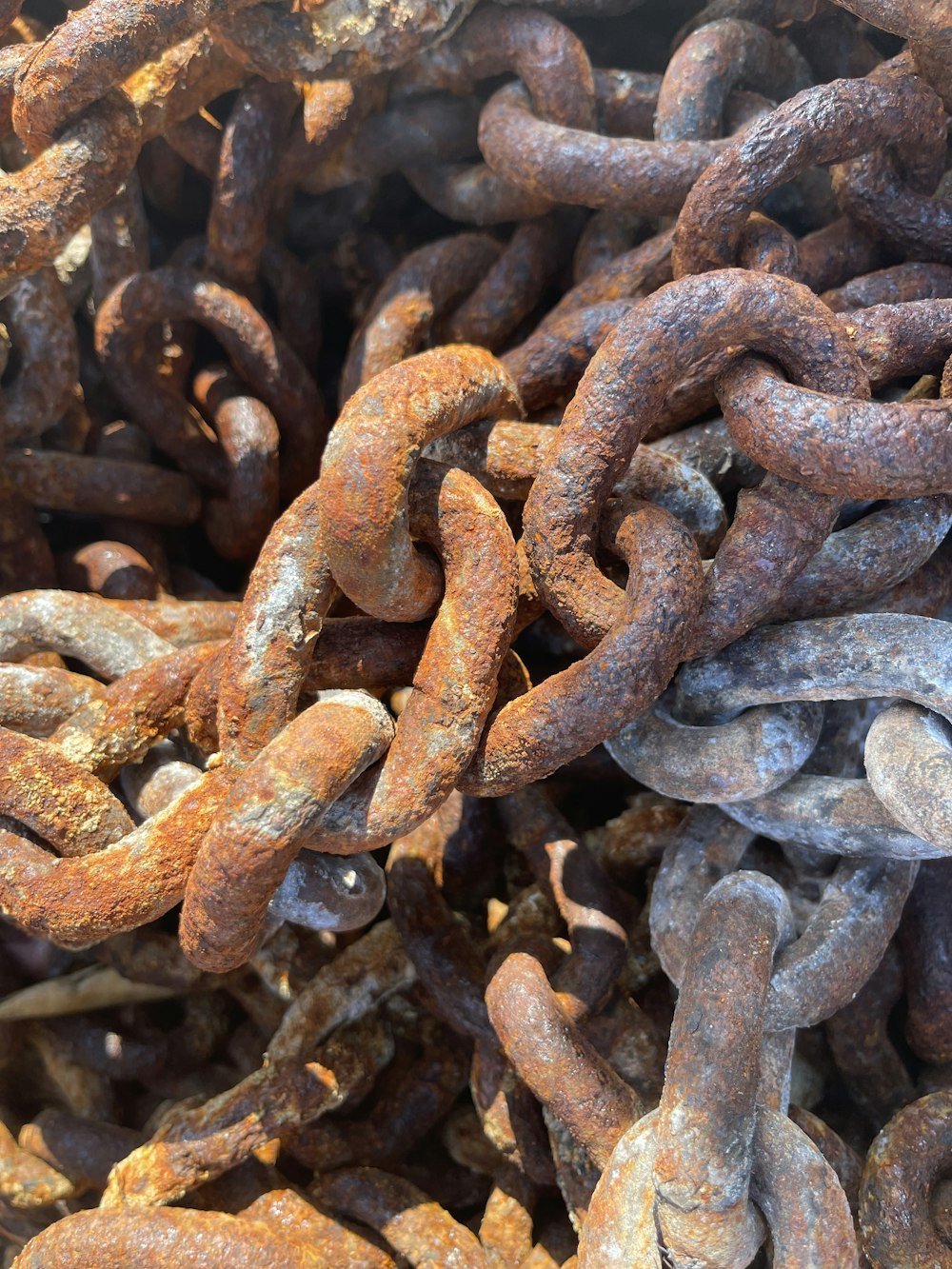 Una pila de cadenas de metal oxidadas sentadas una encima de la otra