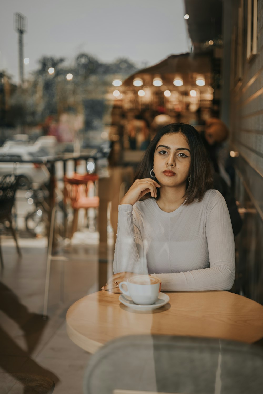 a woman sitting at a table with a cup of coffee