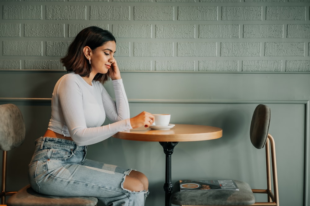 a woman sitting at a table with a cup of coffee